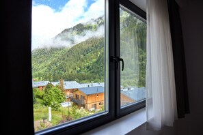 Une fenêtre donnant sur une montagne et un bâtiment.