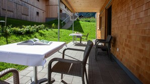 An outdoor patio with a table and chairs, a wooden building, and a staircase leading to a higher level. - 47021 Kollin 2 EG (St. Gallenkirch)