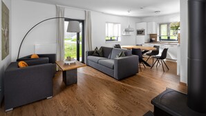 Ein modernes Wohnzimmer mit einem grauen Sofa, einem Holztisch und einem schwarzen Kamin.