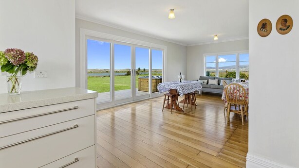A spacious kitchen with large windows, a dining area with a table set for two, and a view of the outdoors.