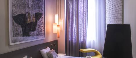 A hotel room with a bed, a sofa, a desk, and a large painting on the wall.