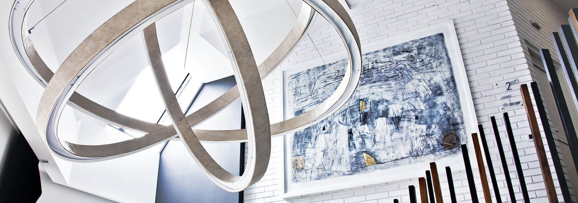 Een modern interieur met een groot abstract schilderij, een geometrische lamp en een witte bakstenen muur.