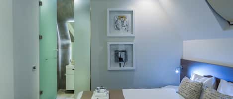 A hotel room with a bed, a nightstand, a mirror, and artwork on the wall.