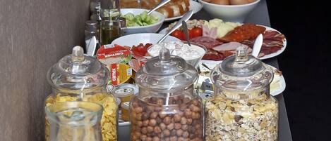 A buffet table with various food items including fruits, bread, and condiments.