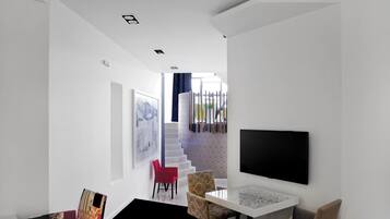 Un salon moderne avec un canapé blanc, un fauteuil rouge, une table basse en marbre et un téléviseur à écran plat fixé au mur.