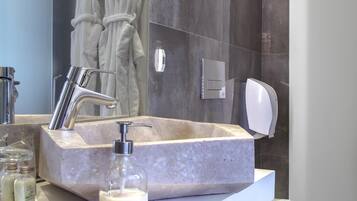 Un baño moderno con lavamanos de mármol, ducha de mano y un inodoro.