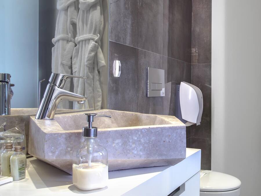 Un baño moderno con lavamanos de mármol, ducha de mano y un inodoro.