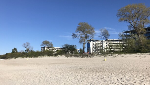 En sandstrand med byggnader i bakgrunden.