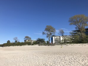 A sandy beach with buildings in the background. - 2 room apartment on the beach (Kolobrzeg)