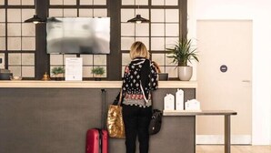 A reception area with a counter, a TV screen, a potted plant, and a wooden floor.