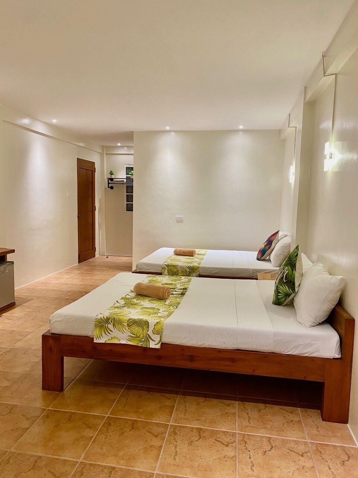 A hotel room with a large bed, a bedside table, and a view of the hallway.