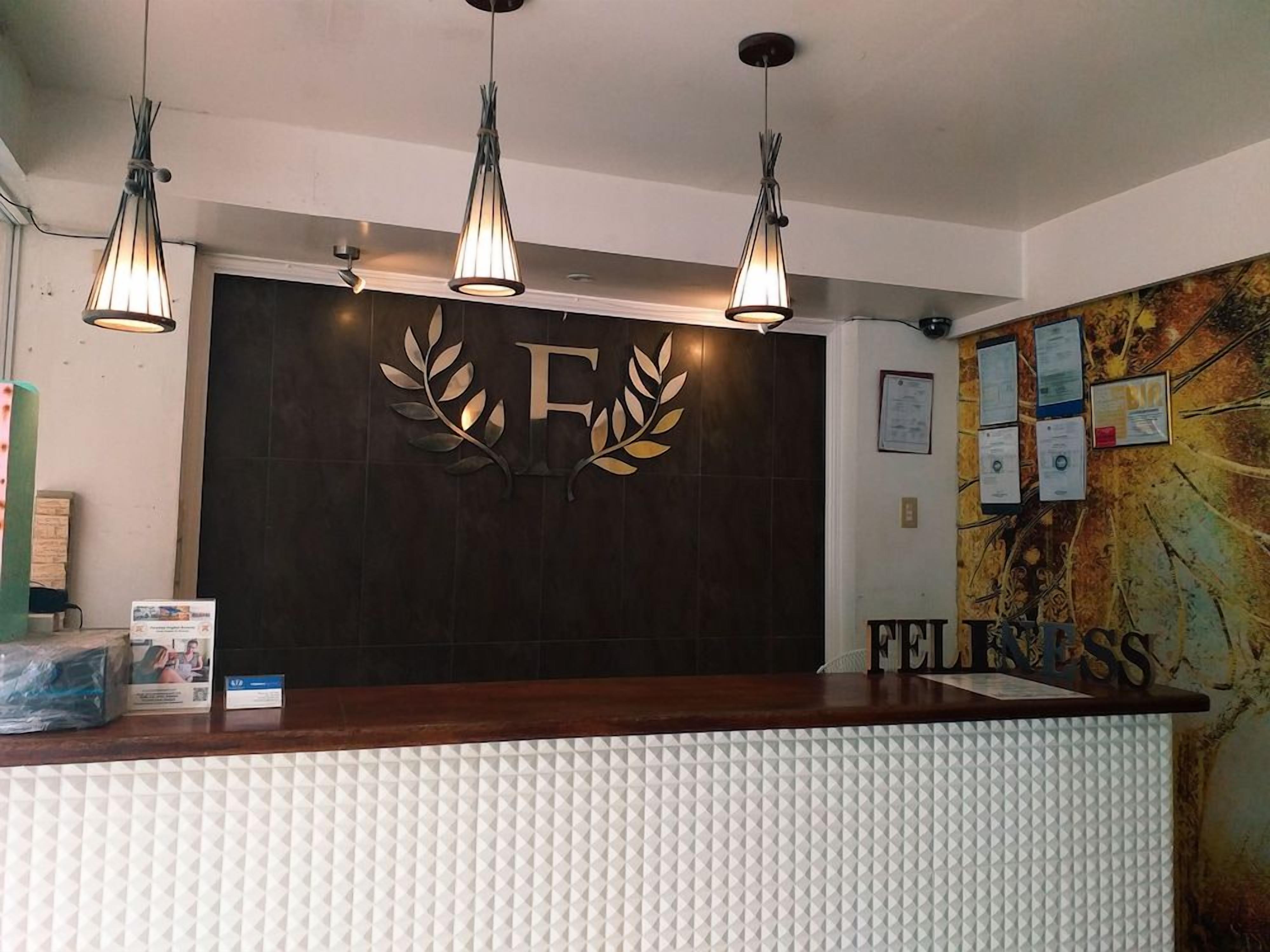 A reception desk with a dark wood finish, a white textured wall, and a large 'F' with a leaf design above it.