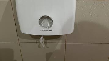 Un dispensador de jabón blanco fijado a una pared de azulejos.