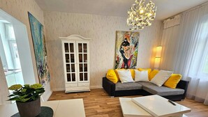 Una sala moderna con un sofá seccional, un mueble blanco y una mesa de comedor.