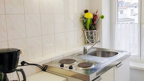 Una kitchenette compacta con un lavabo, una cafetera y una estufa pequeña.