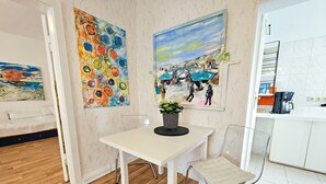 Una habitación con una mesa blanca, una silla, una cama y dos cuadros en la pared.