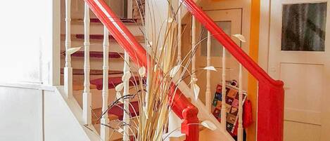 A staircase with white railings and red accents, leading to a door with a framed picture.