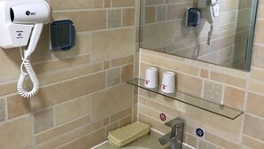 Une salle de bain équipée d’un lavabo, d’un miroir, d’un sèche-cheveux et d’un téléphone.