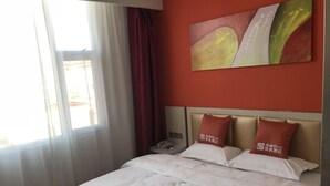 Une chambre d’hôtel avec un lit, une table de chevet, un téléphone et un tableau au mur.
