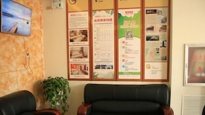 Une salle d’attente équipée d’un téléviseur, d’un panneau d’affichage où sont accrochées diverses informations, de deux canapés en cuir et d’une table basse.