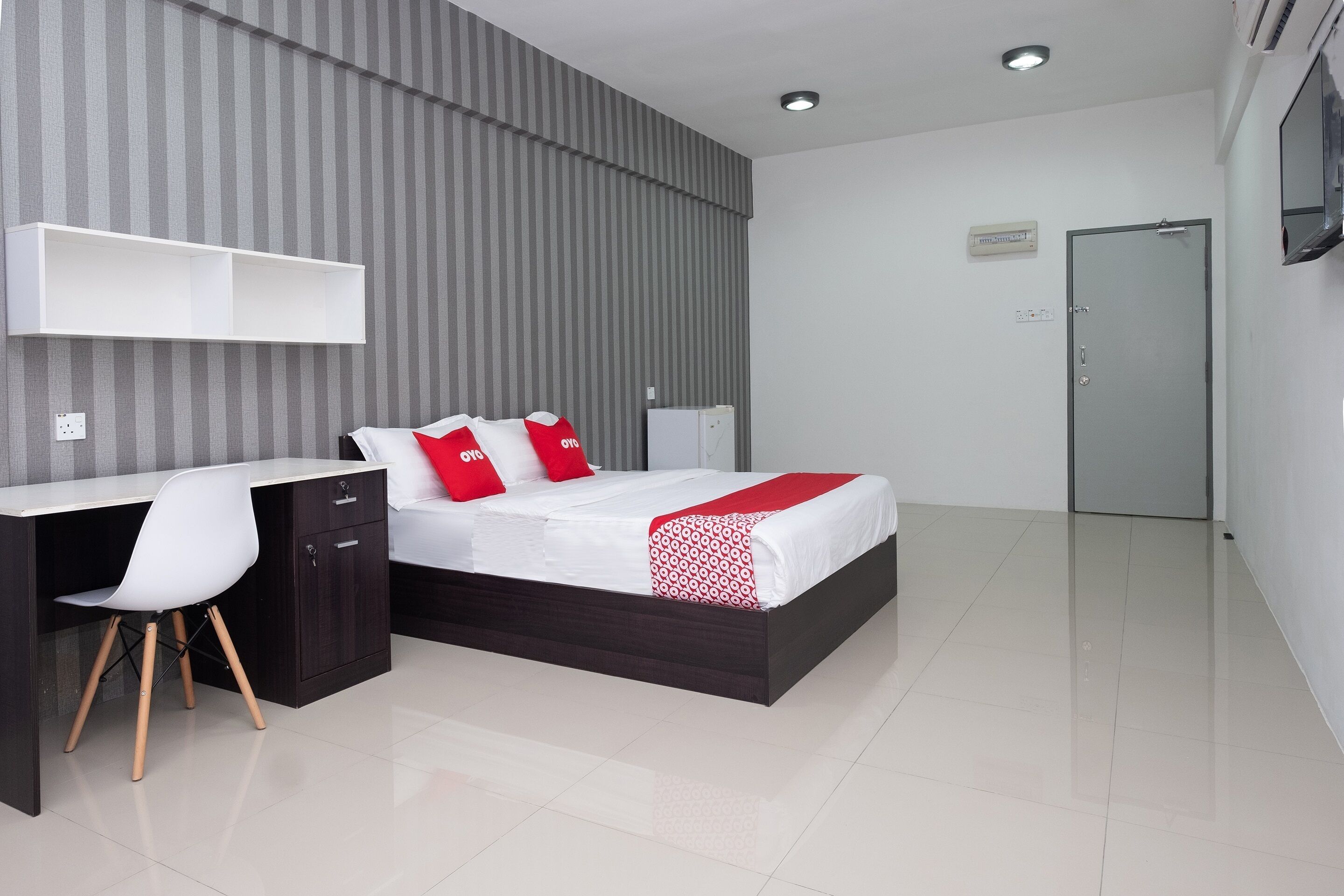 Ein modernes Hotelzimmer mit Bett, Schreibtisch, Stuhl und Kleiderschrank.