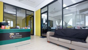 Una recepción con el letrero de Summer Inn Homestay, un sofá color beige y ventanas grandes.
