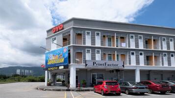 A multi-story building with a 'PrintFactor' sign, a 'Super Clean' advertisement, and several parked cars.
