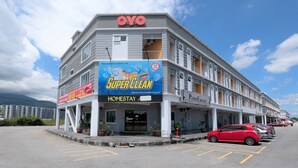 Un edificio de varios pisos con un letrero que dice 'Super Clean', un letrero que dice '24 JAM' y un letrero que dice 'HOMESTAY'.
