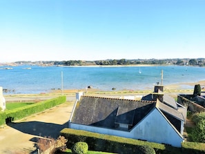A coastal view with a white building, a clear sky, and calm sea.