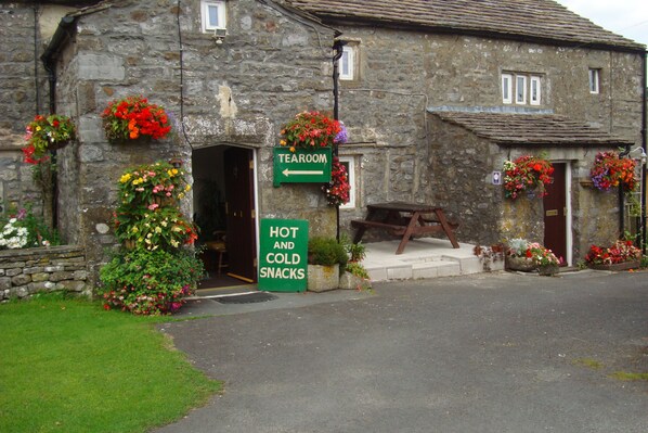 A stone building with a sign for a tearoom and a sign for hot and cold snacks.