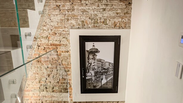 Un escalier avec un mur en pierre et une photographie en noir et blanc encadrée.