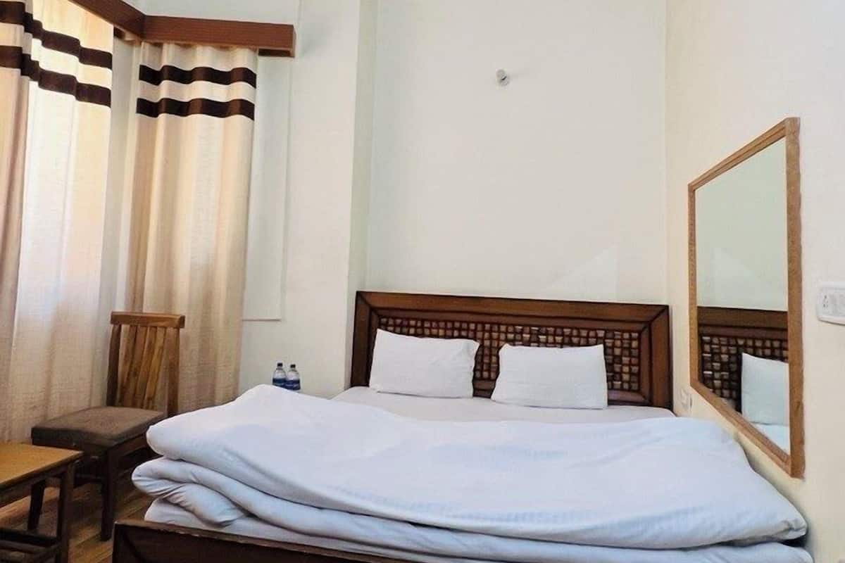 A hotel room with a wooden bed, a wooden headboard, a large mirror, and a ceiling with a decorative design.