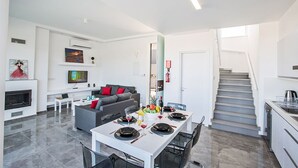 Un espacio de estar moderno con comedor, cocina y escalera.