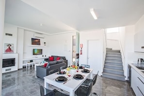 A modern living space with a dining area, kitchen, and staircase.