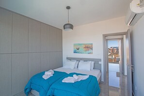 A modern hotel room with a large bed, a painting on the wall, and a view through an open door.