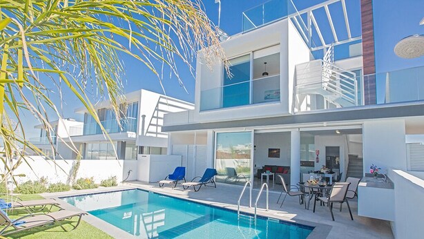 Un edificio moderno de dos pisos con piscina, mobiliario exterior y una escalera que conduce a un nivel superior.