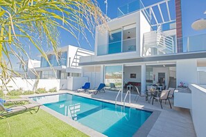 A modern two-story building with a swimming pool, outdoor seating, and a staircase leading to an upper level.