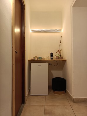 Uma cozinha compacta equipada com geladeira, pia e bancada com diversos objetos.