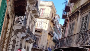 Una stretta via fiancheggiata da edifici, con balconi e un cielo azzurro limpido.