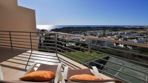 A balcony with two lounge chairs and a view of the sea and town. - Flat Amora OCV - Ocean View (Albufeira)