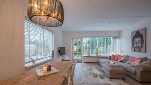 A modern living room with a wooden dining table, a beige sofa, and a cowhide rug.