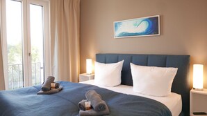 A hotel room with a bed, two pillows, a headboard, a nightstand, a remote control, and a painting on the wall. - Baabe Villen Ensemble FeWo 34 Pura Vida Ref. 215429 (Baabe)