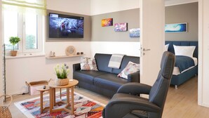 A modern living room with a sofa, a coffee table, and a TV mounted on the wall. - Baabe Villen Ensemble FeWo 34 Pura Vida Ref. 215429 (Baabe)