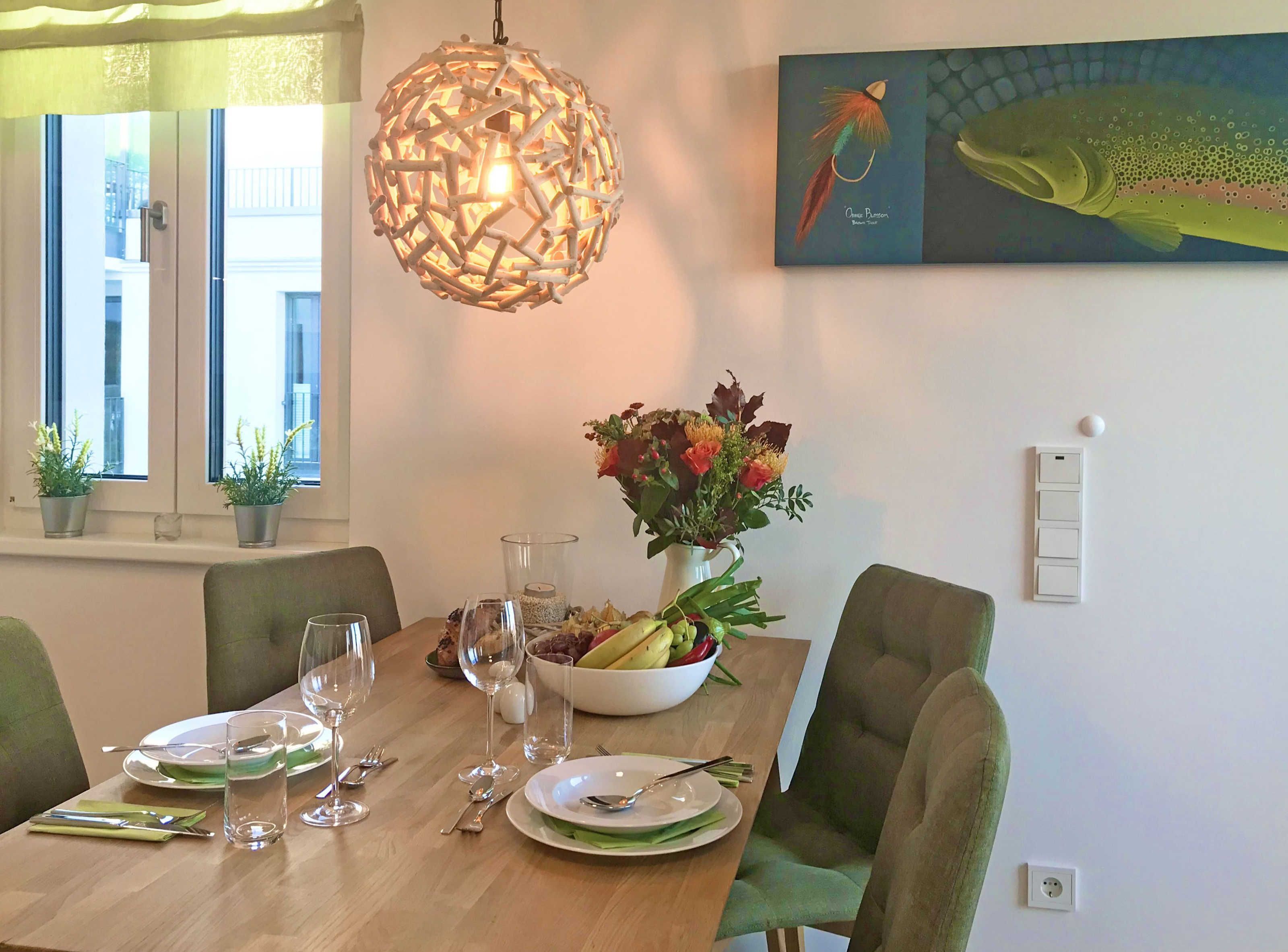 A dining table set with plates, cutlery, and a bowl of fruit.