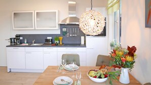 A modern kitchen with white cabinets, a stainless steel range hood, and a hanging light fixture. - Baabe Villen Ensemble FeWo 34 Pura Vida Ref. 215429 (Baabe)