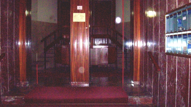 Un ascensor tenuemente iluminado con alfombra roja y paredes de madera.