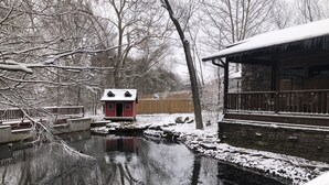 Un espace extérieur enneigé comprenant une petite maison rouge, un bâtiment en pierre et une terrasse en bois.