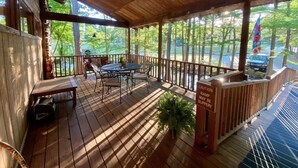Une terrasse en bois avec une table et des chaises, un banc et un panneau d’avertissement indiquant que la rampe est glissante.