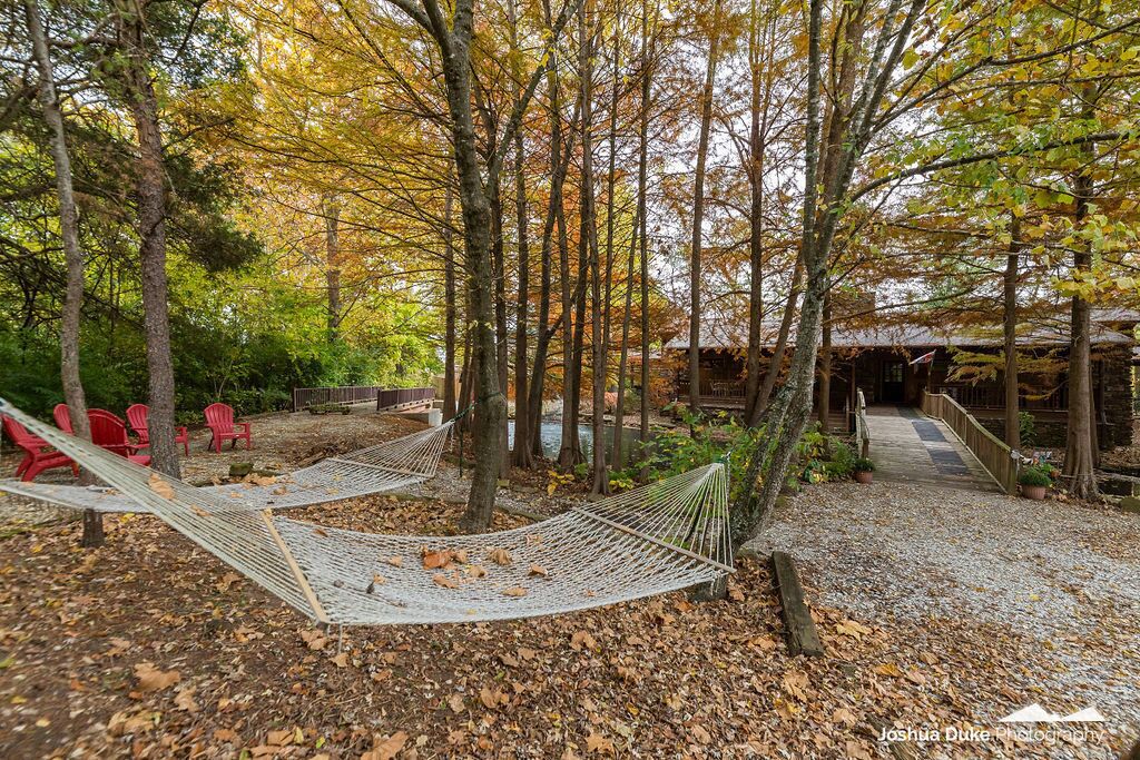 A hammock in a wooded area with a wooden structure in the background.