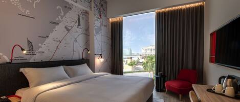 Habitación de hotel con una cama grande, un escritorio con una silla, un mapa en la pared y vistas a la ciudad.